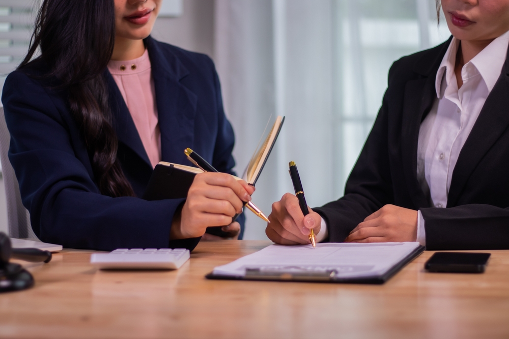 Female executives and female lawyer signing a document together.